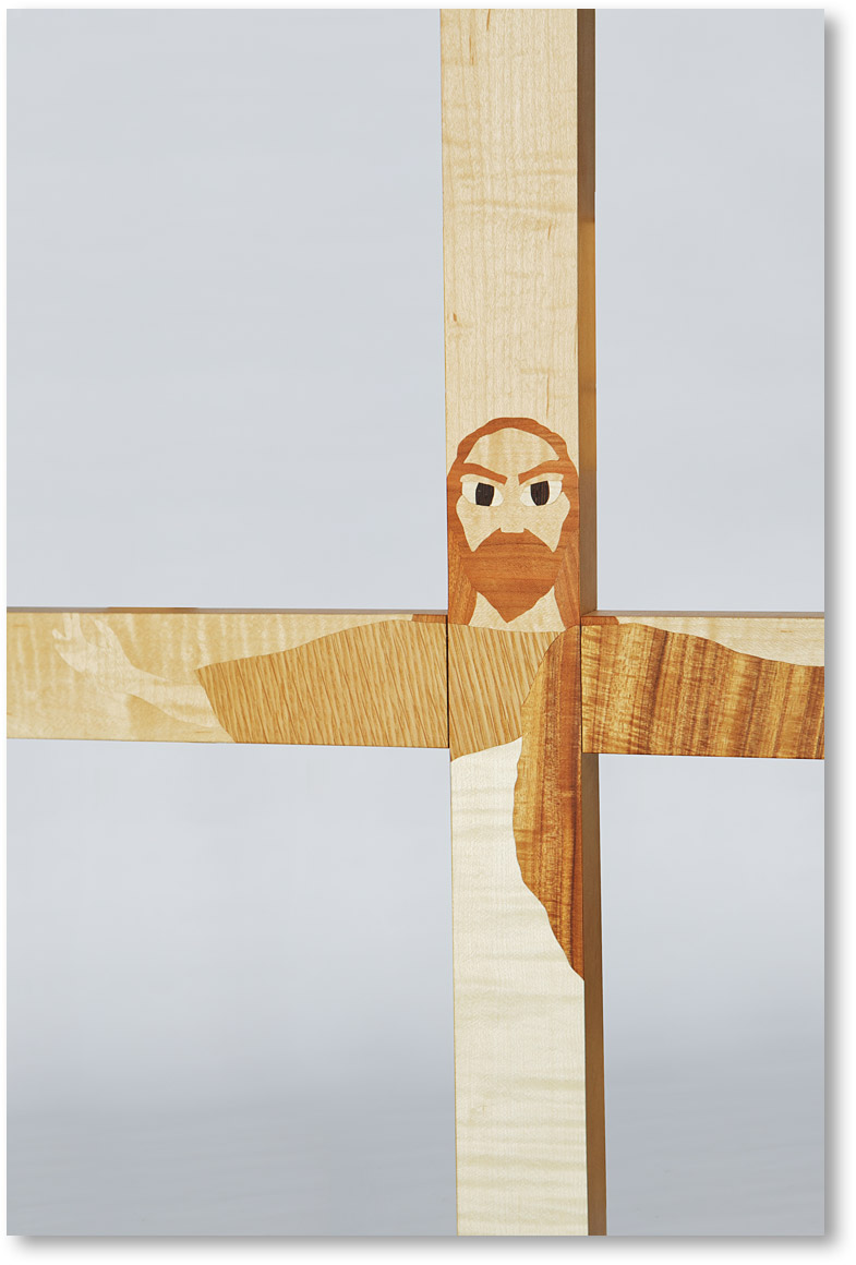 メープルの十字架にオークやチェリーを用いて図柄を表現しています。